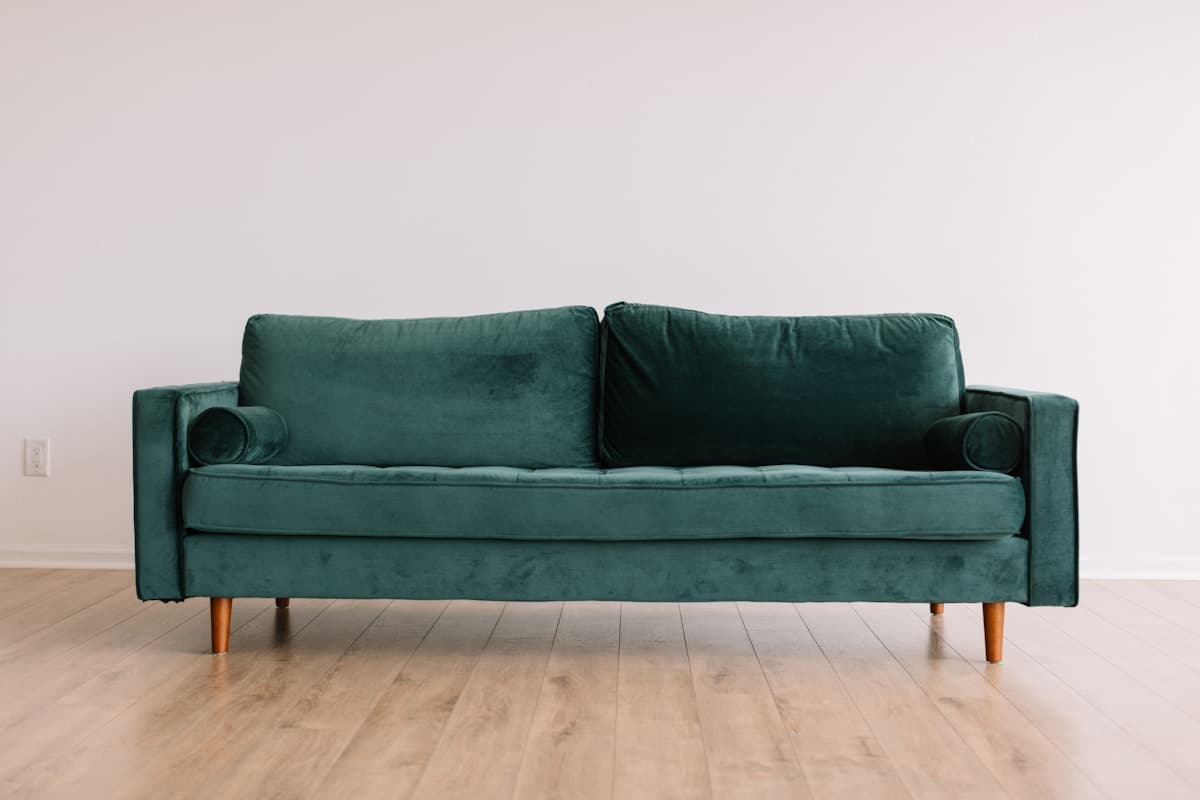 Dunkelgrünes Sofa mit zwei Sitzpolstern und Holzfüßen